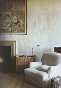 a white chair sitting in front of a fire place next to a painting on the wall