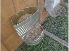 a metal bucket filled with gravel next to a chicken coop