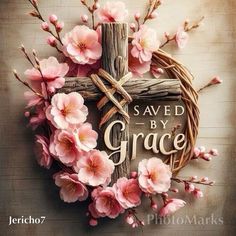 a cross with pink flowers on it and the words saved by grace written in wood