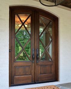 the front door to a house with two doors and a rug on the ground in front of it