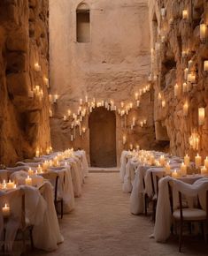 an indoor dining area with tables and chairs covered in white linens, lit by candles