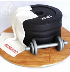 a cake that is on top of a wooden board with a towel and two dumbbells