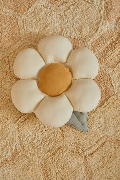 a white flower shaped pillow sitting on top of a bed