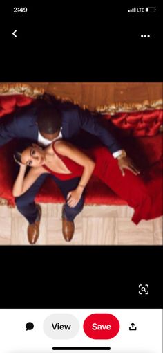 a man and woman laying on top of a red couch with their arms around each other