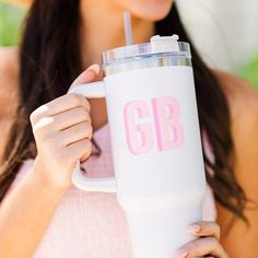 a woman holding a white cup with pink letters on it and a straw in her hand