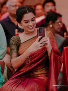 a woman in a red sari is looking at her cell phone while sitting down