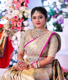 a woman sitting on top of a couch wearing a white and pink dress with gold jewelry