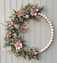 a wreath made out of fake flowers and greenery hangs on the wall next to a door