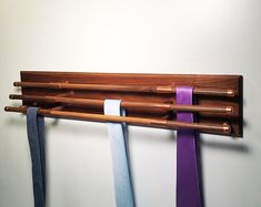 three ties hang on a coat rack made out of wood