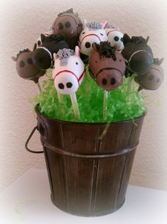 a bucket filled with cake pops covered in chocolate and topped with farm animal faces on them