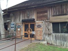 an old wooden building with many signs on the front and side doors that are open