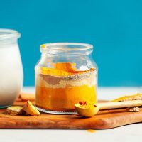 two jars filled with food sitting on top of a wooden cutting board