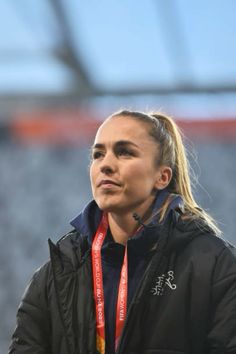 a woman with a medal around her neck looking off into the distance while standing in front of an empty stadium