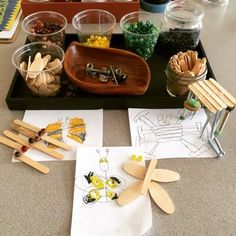 an assortment of wooden spoons on a tray with paper and other crafting supplies