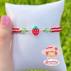 a person holding onto a white pillow with a strawberry bracelet on it