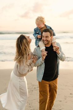 a man and woman holding a baby on the beach