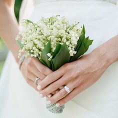 a bride holding a bouquet of flowers in her hands with wedding rings on her wrist