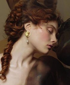 a woman with long red hair wearing gold earrings