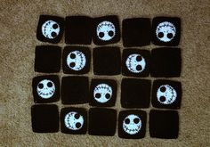 there are knitted squares that have been decorated with skulls and faces on them, sitting on the floor