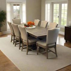 a dining room table with chairs and a bowl of fruit on it