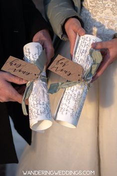 the bride and groom are holding two wrapped gift boxes with writing on them, tied in twine