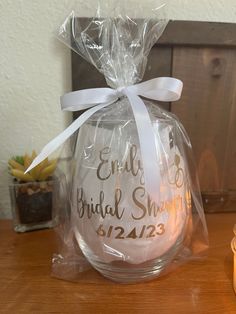 a clear glass ornament wrapped in plastic with a white ribbon around it on a wooden table