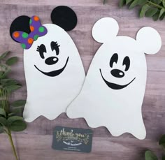 two white ghost costumes with mickey mouse heads on them, one has a purple bow and the other has a green polka dot headband