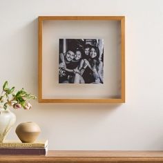 a wooden frame holding a black and white photo next to a vase with flowers