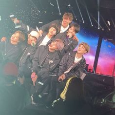 a group of young men standing next to each other on top of a stage with confetti in the air