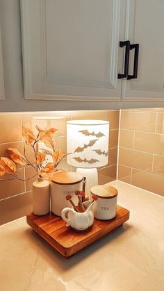 a wooden tray with two mugs on it and a lamp in the corner next to it