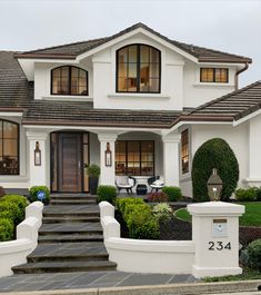 a white house with two story windows and steps leading up to the front door area