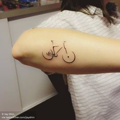 a woman with a tattoo on her arm that has a bike on it and the word love written in cursive writing