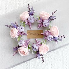 flowers arranged in the shape of a wreath with a name tag attached to it on a white surface