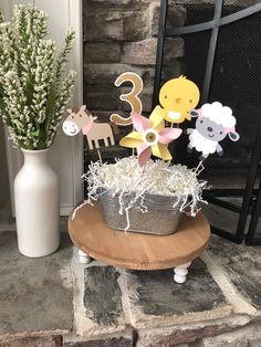 a cake topper in the shape of animals and sheep is sitting on a table next to a vase with baby's breath flowers