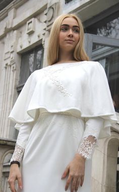 a woman in a white dress is standing outside