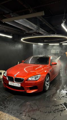 a red car being washed in a garage by a man with a blow dryer