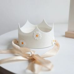 a white crown sitting on top of a table next to a ribbon tied around it