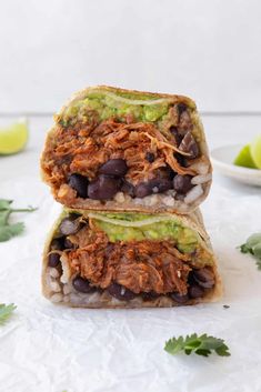 two burritos stacked on top of each other with black beans and avocado