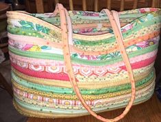 a large multicolored bag sitting on top of a wooden table next to a chair