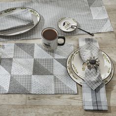 a table set with place mats, plates and cups