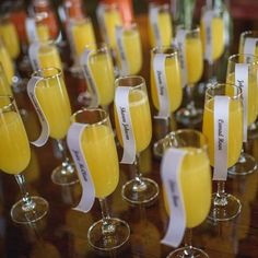 many glasses filled with yellow liquid on top of a wooden table next to each other