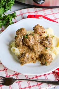 a white plate topped with meatballs and mashed potatoes on top of a red checkered table cloth