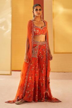 Orangish red silk organza cape with floral print and zardosi and pitta embroidery. Comes with sharara and a blouse.
Components: 3
Pattern: Printed, Embroidered
Type Of Work: Floral, Zardosi, Pitta
Neckline: Sweetheart
Sleeve Type: Cape : Flared Sleeves, Blouse : Sleeveless
Fabric: Silk organza
Color: Orange,Red
Other Details: 
Pocket detailing on sharara
Note : Outfit worn by the model on the left is not for sale.
Occasion: Mehendi and Haldi - Aza Fashions Orange Saree Set With Intricate Embroidery, Orange Festive Set With Intricate Embroidery, Orange Diwali Sets With Intricate Embroidery, Bollywood Style Orange Embroidered Choli, Embroidered Orange Choli For Navratri, Bollywood Style Front Open Embroidered Sets, Bollywood Style Front Open Sets With Intricate Embroidery, Eid Front Open Sets With Floral Embroidery, Eid Sets With Floral Embroidery And Front Open Design