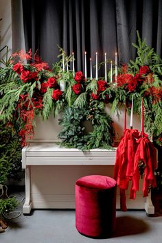 a white piano sitting next to a bunch of red flowers and greenery on top of it