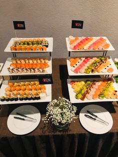 a table topped with lots of different types of sushi and other foods on plates