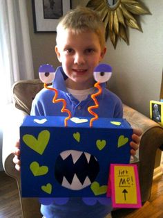 a young boy holding up a box with decorations on it