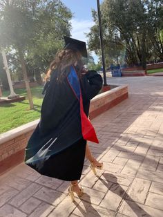 a woman in a graduation gown walking down the street