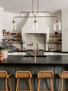 an image of a kitchen with stools in front of the island and stove top