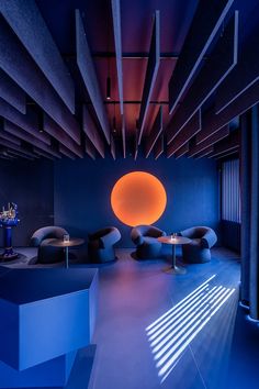 the room is lit up with bright blue light and has round shaped furniture in it