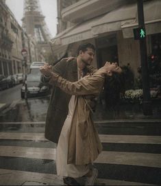 a man and woman dancing in the rain with an eiffel tower in the background